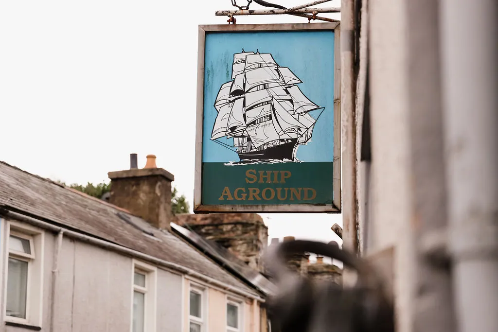 The Ship Aground hanging sign, a tall ship in full sail, against the sky